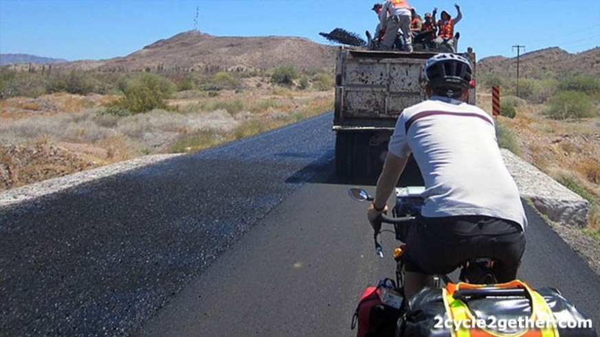 Road workers laying asphalt (and throwing peace signs) on a highway in Baja.